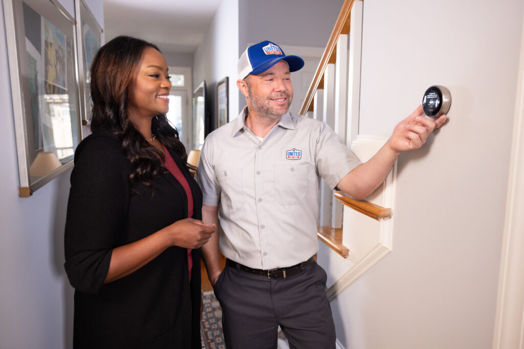 UAT technician and homeowner looking at a smart thermostat
