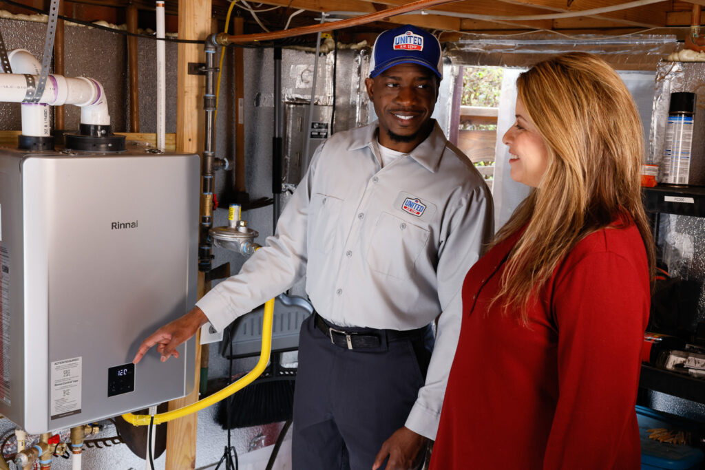 UAT technician speaking with homeowner while pointing to her tankless water heater