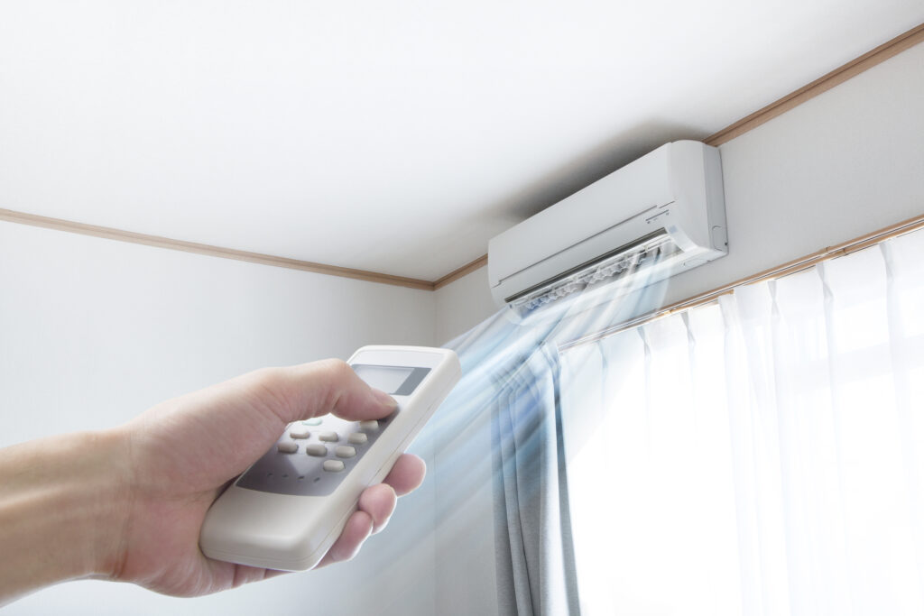 Ductless mini-split blowing cold air and a hand holding the remote