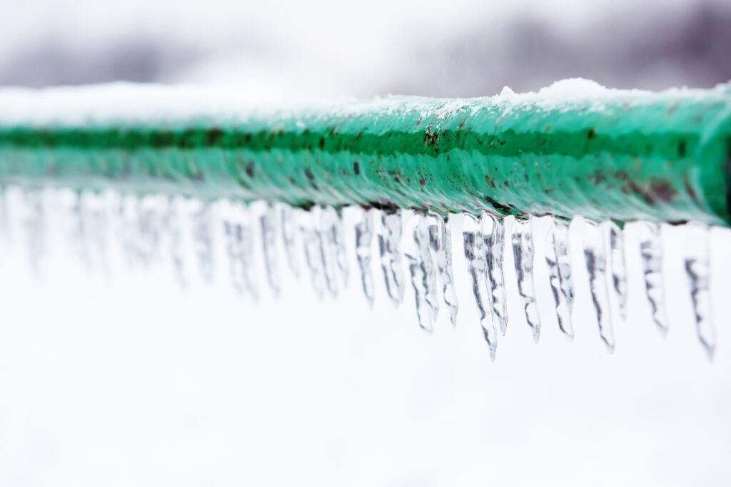 Closeup of exposed frozen pipe with icicles