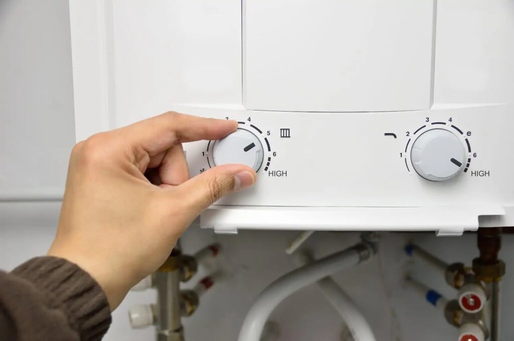 Closeup of hand adjusting a dial on a water heater