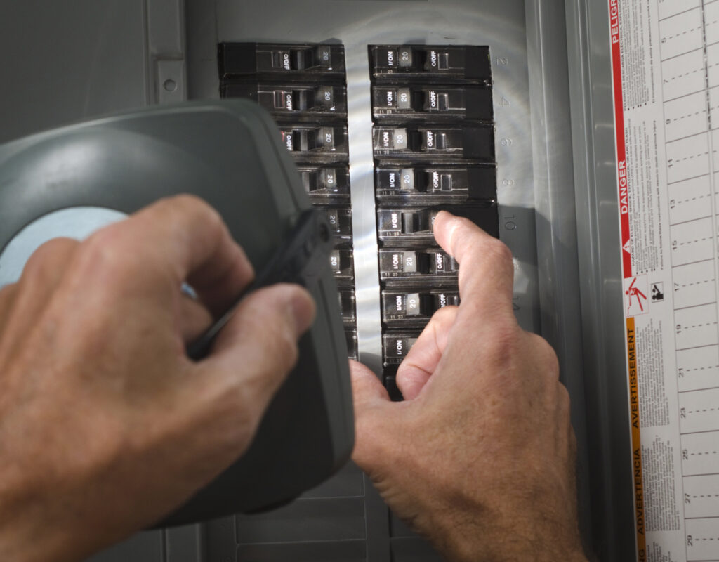 man resetting circuit breaker at residential service panel