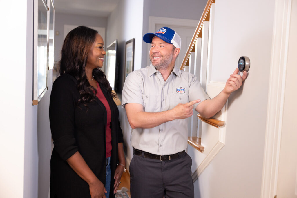 UAT technician showing a woman her new smart thermostat