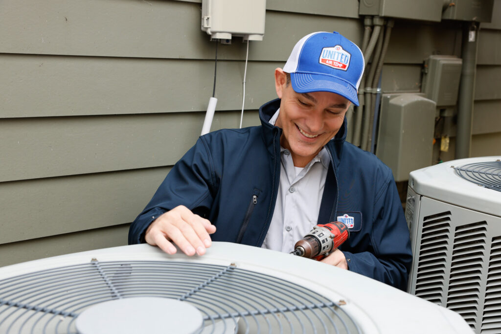 Technician installing an outdoor AC unit next to a home.