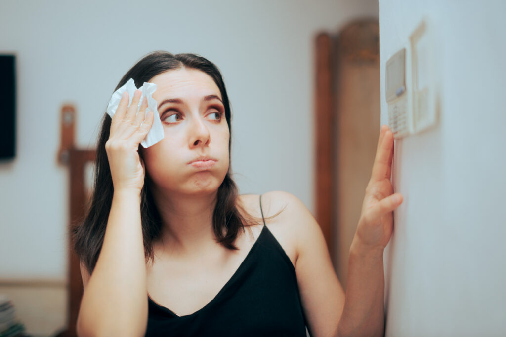 Women sweating and adjusting the thermostat