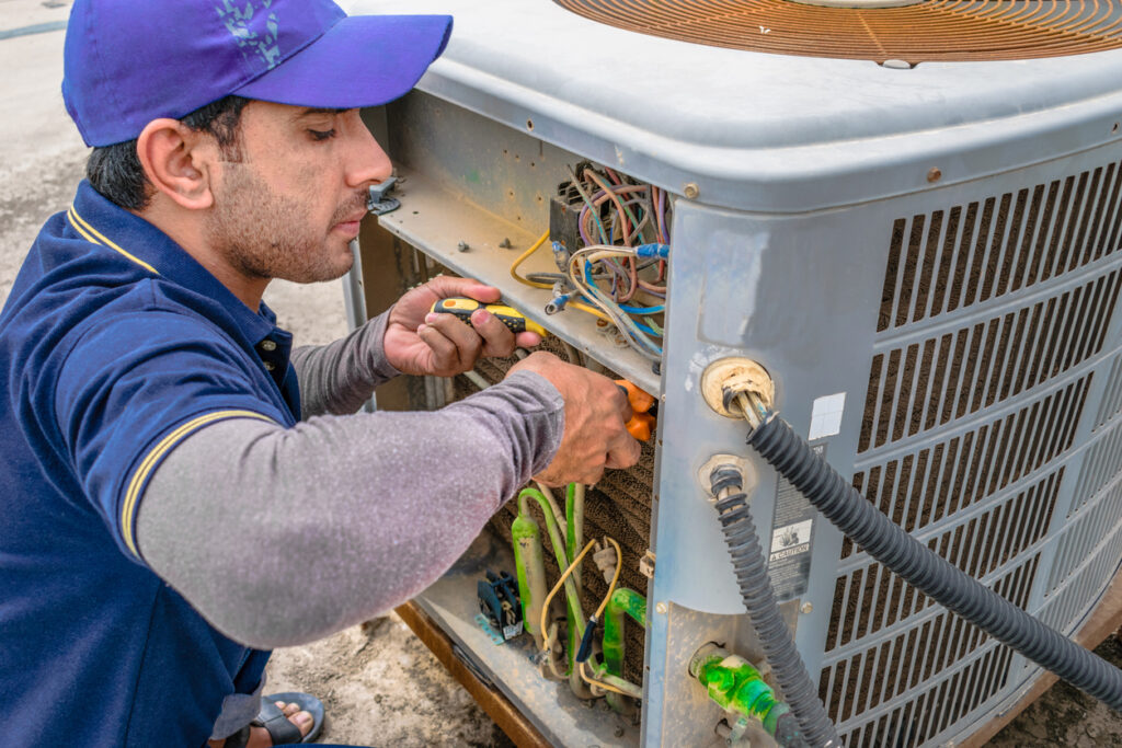 HVAC technician maintaining an air conditioner
