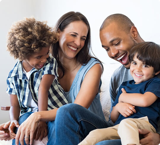 Parents holding two young kids in laps laughing